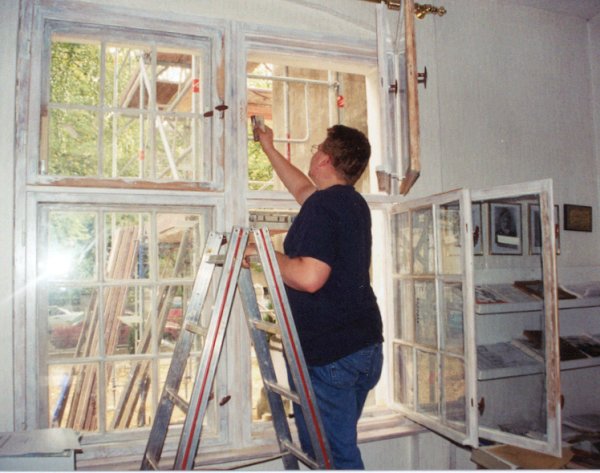 Craftsman repairing the front windows of the Mission House